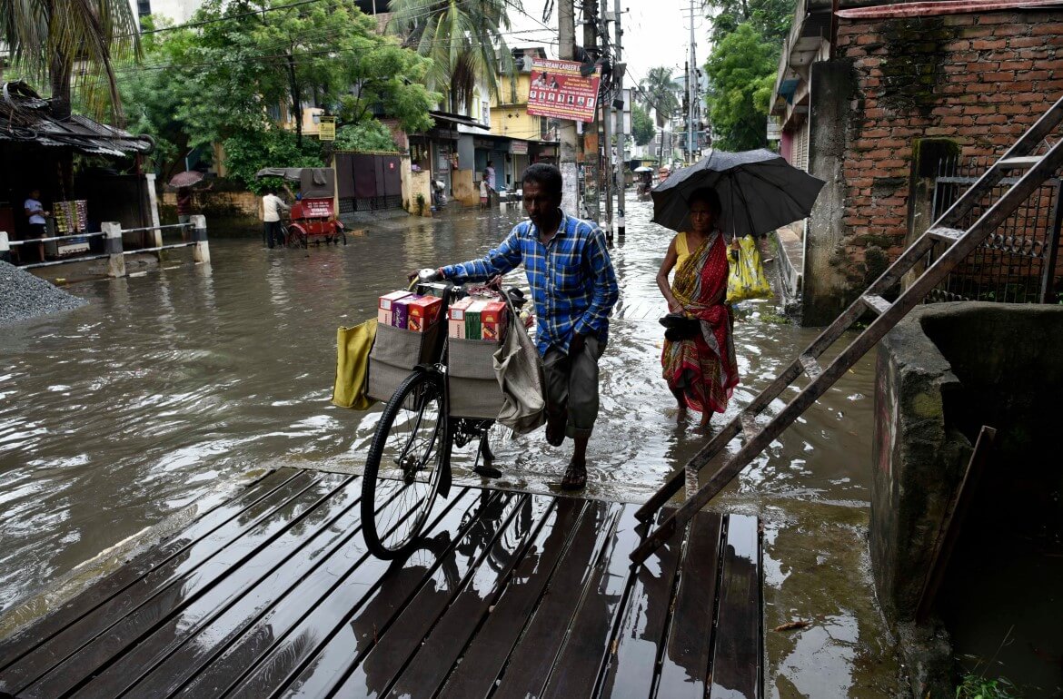 Commuters wade through flooded streets after heavy rainfall in Guwahati, Assam. Photo by Shutterstock.