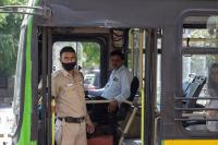 A bus driver as seen from outside the door of the bus while a police man stands inside