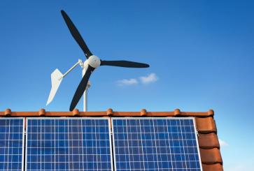 small windmill for small-scale wind energy above a house. Solar panels also atop roof.