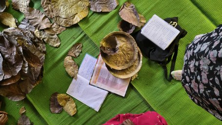 Dried Sal leaves, cash registers and finished plates kept on the floor during a SHG meeting