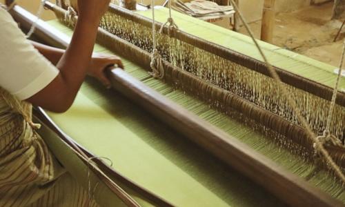 Woman weaves on a loom 