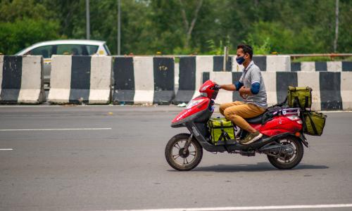Delivery worker on a bike in the heat in Delhi