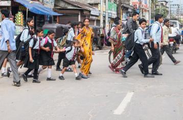 School children cross a road amidst traffic. Photo by Shutterstock.