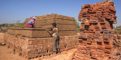 Workers arrange raw clay bricks manually for baking. Photo by Hari Mahidhar/Shutterstock.