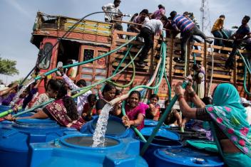 Residents climb on a municipal water tanker to fill their containers. Photo by Manoej Paateel/Shutterstock